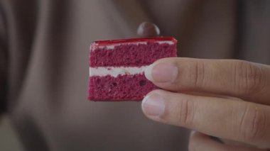 Adamın biri kremalı kırmızı kadife kek gösteriyor..