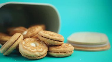 Bazıları içeride kalırken, bir kap mavi arka plana kurabiye döker..