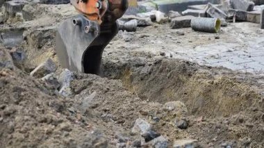 Bir makine, yakınlarda enkaz varken bir inşaat alanında toprağı kazıyor..