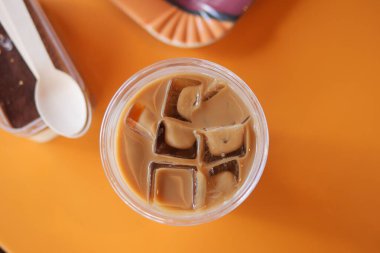 Buz küplü buzlu kahve parlak turuncu bir masada oturur..