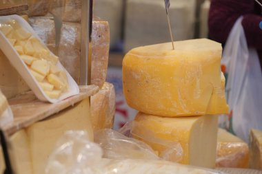 İnsanlar canlı bir bölgedeki pazarda peynir seçeneklerini araştırıyorlar..