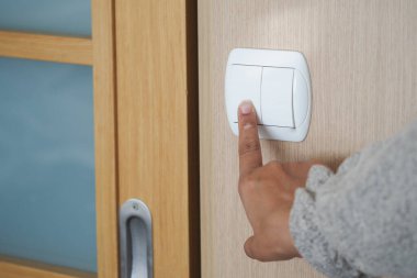 Biri ahşap bir kapının lambasını açıyor..