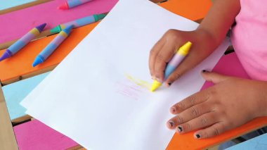 Çocuk dışarıdaki boş kağıtlarda resim yapmak için boya kalemleri kullanıyor..