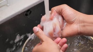 İnsan, yemek hazırlamak için lavaboda akan suyun altında balık temizler..