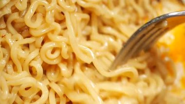 Bir insan mutfakta yumurtalarla erişte pişirir..