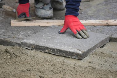 Bir işçi beton levhayı ıslak karışıma yerleştirmek için ellerini kullanır..