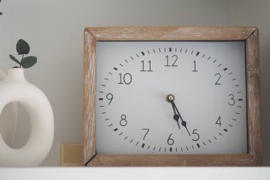 Saat 5: 30 'u gösteriyor. Rafta basit bir tasarım var..