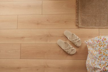 Terlikler ve çiçek yastığı tahta zeminde dinleniyor..