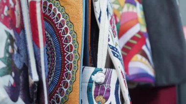 İnsanlar yerel bir pazarda çeşitli renkli kumaşlar görüyor ve satın alıyorlar..