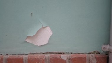 Duvarda eksik bir boya parçası ve üssün yakınında açıkta kalmış bir madde var..