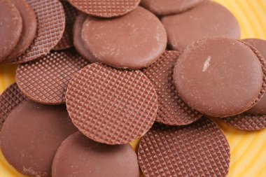 Birçok yuvarlak çikolata diskleri mutfaktaki sarı bir tabağa konur..