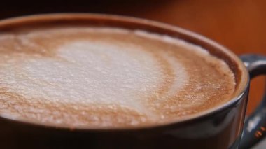 Yakın çekim bir fincan kahvenin latte sanatıyla doldurulduğunu gösteriyor..