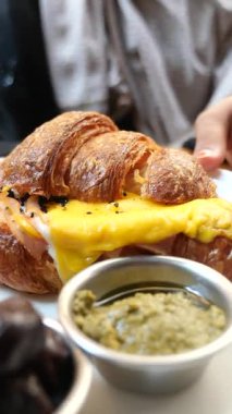 Bir kafede yumurta ve sosla dolu kruvasanın tadını çıkarıyorum..