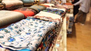 Çeşitli renk ve desenlerden oluşan eşarplar bir mağazaya düzgünce yerleştirilir.