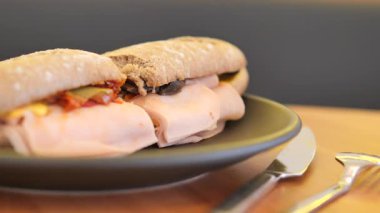 Bir insan bir kafede et ve malzemeyle sandviçi ısırır..