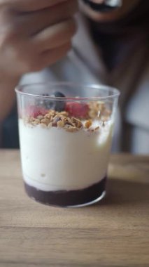 Bir insan masada meyveli ve tahıllı yoğurt yer..