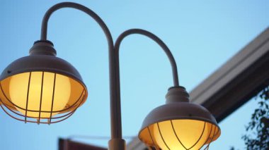 İki sokak lambası bir binanın girişinin yanında gece gibi parlıyor..