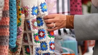 Bir el renk dolu canlı bir pazarda tığ işi bir nesneye uzanır..