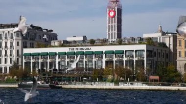 Ziyaretçiler İstanbul 'daki Yarımada Oteli' nin önünden geçen tekneleri izliyorlar.