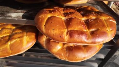 Fırıncılar sabah güneşinde metal bir rafta sıcak ekmek sergiliyorlar..