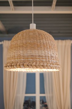 Işık perdeli bir odada tavandan sarkan bir sepet lamba..