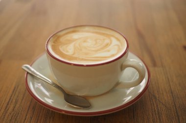 Bir kahve fincanı ahşap bir masada oturur. İçkinin bir girdabı var..