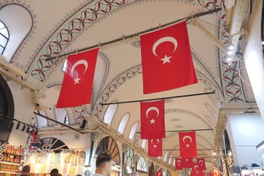 İstanbul 'da kalabalık bir pazarda insanlar Türk bayrakları altında yürüyor.