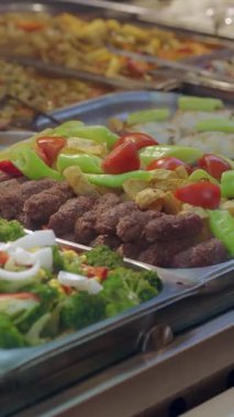 İnsanlar öğlen vakti kafeteryada çeşitli yemekler seçiyorlar..