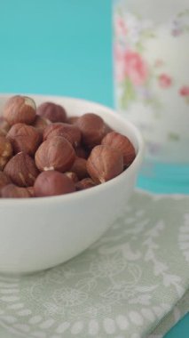 Fındıklar beyaz bir kasede mavi bir masada içkiyle gösterilir..