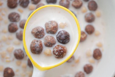 Bir kaşık mısır gevreğini açık mutfak alanında sütle birlikte taşır..