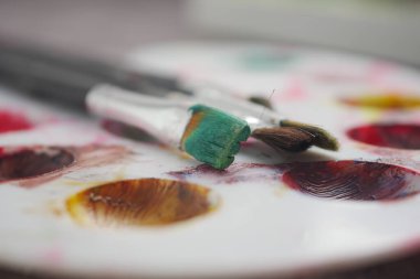 Boya fırçaları ve çeşitli renklerde boyalar bir masanın üzerinde duruyor..