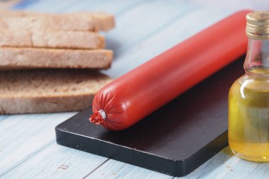 Sosis dilimler ve bir şişe yağ ile birlikte kesim tahtasının üzerinde..