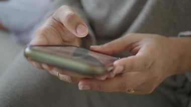 Bir kadın kanepede otururken akıllı telefonuna bakar..