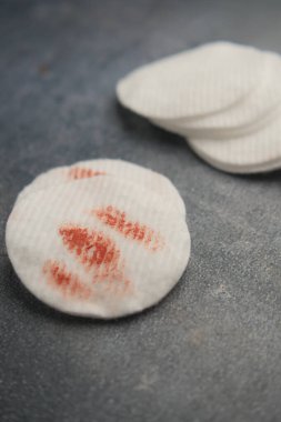 Pamuk mermileri koyu bir yüzeye yerleştirilir ve makyaj izleri görünür..