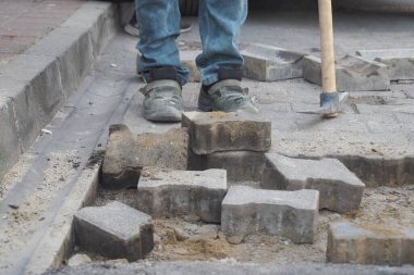 Yoğun bir bölgede kaldırımda taşları değiştiren bir kişi var..