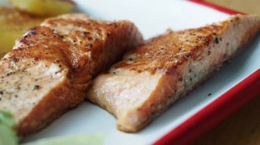 İki parça somon pişirilir ve kenarları olan bir tabağa yerleştirilir..