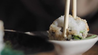 Birisi restoranda suşi toplamak için çubuk kullanıyor..