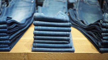Birçok katlanmış kot pantolon bir masanın üzerinde düzgünce düzenlenir..