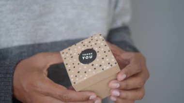 Bir insan üzerinde teşekkür etiketi olan paketlenmiş bir hediye kutusu gösterir..