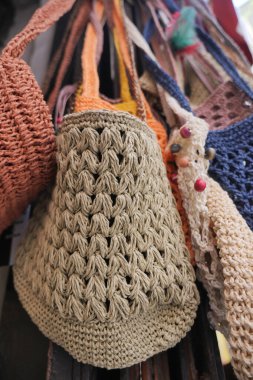 Birkaç el yapımı çanta gün içinde bir markette asılı duruyor..