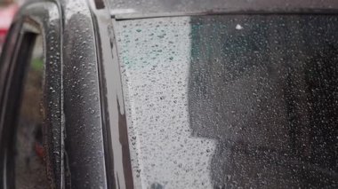 Bulutlar gökyüzünü doldururken yağmur damlaları arabanın camını kaplıyor..