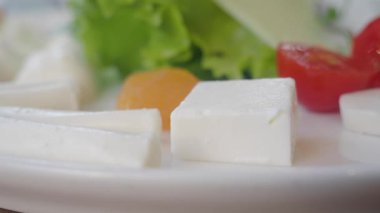 Peynir, marul ve domatesler öğle yemeği sırasında beyaz bir tabakta sıralanır..