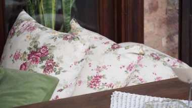 Çiçek yastıklar bir bahçe alanındaki ahşap bir masanın üzerine konur..