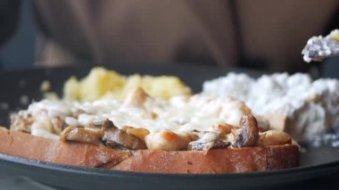 Bugün bir kişi kafede mantarlı ve peynirli tost yiyor..