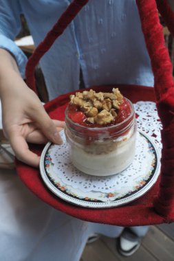 Bir insan elinde bir kavanoz dolusu meyve ve fındık tutar..