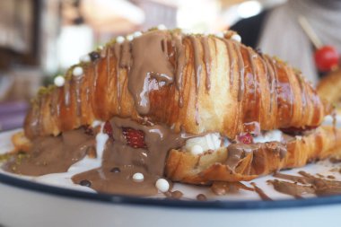 Çikolata dolu bir kruvasan açık havada beyaz bir tabakta oturur..