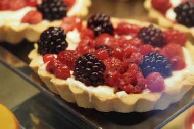 Ahududu ve böğürtlenli taze meyveli tart bir fırın vitrininde duruyor..