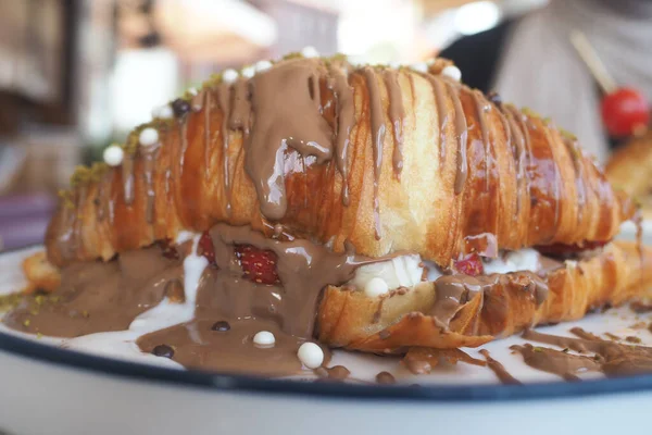 Çikolata dolu bir kruvasan açık havada beyaz bir tabakta oturur..