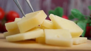 Taze domates ve otların yanında dilimlenmiş peynir..