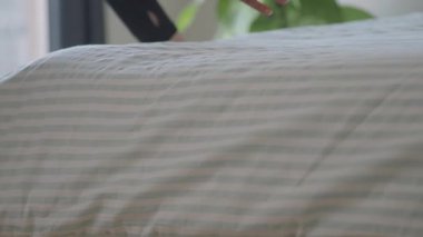 Bir kişi yatağı temiz çarşaflarla ve yastıklarla hazırlıyor..